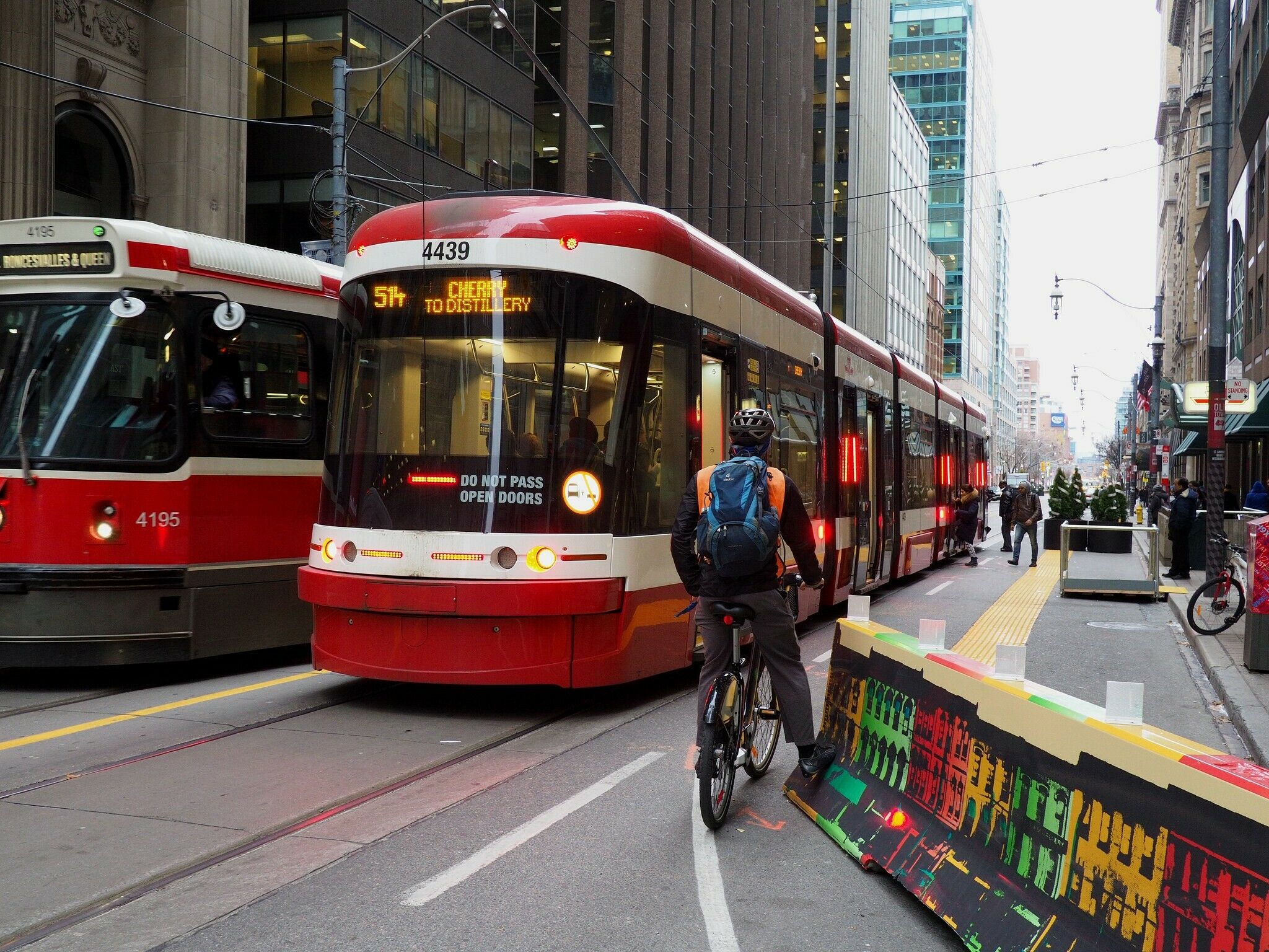 A cyclist waiting behind the open doors of a streetcar along King Street. Thanks City of Toronto Flickr!