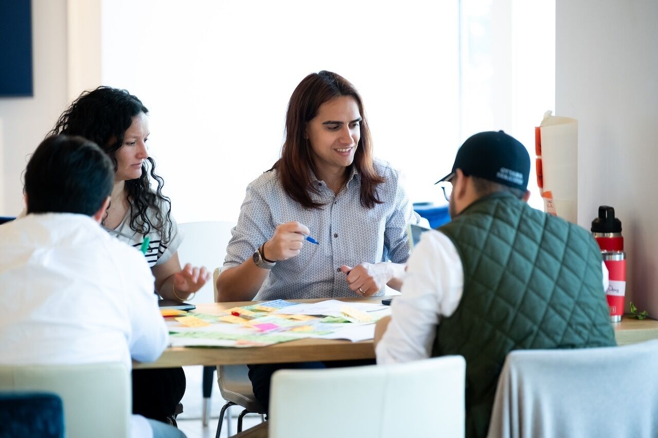 Side view of four people around a table writing on sticky notes