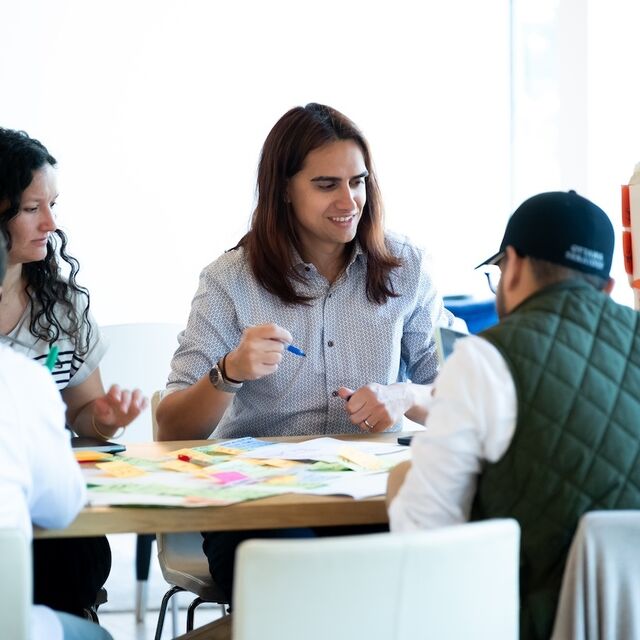 Side view of four people around a table writing on sticky notes