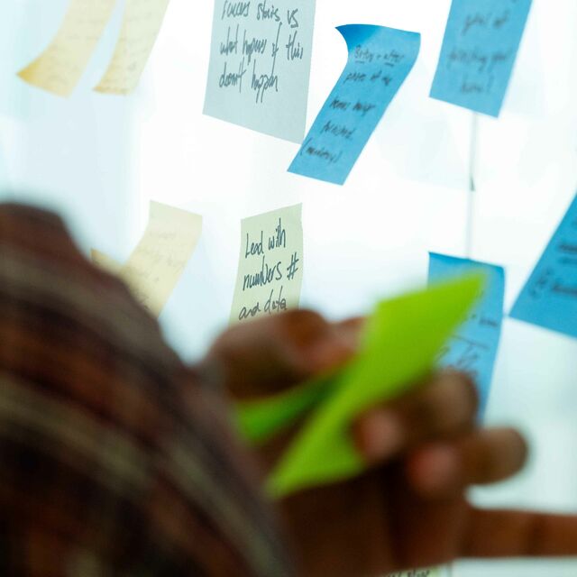 A persons hand putting a stickie on a wall