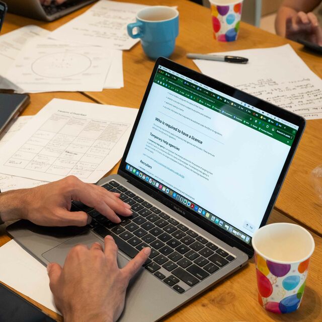 A person using a laptop to visit a government website shot from behind so that only their hands are visible