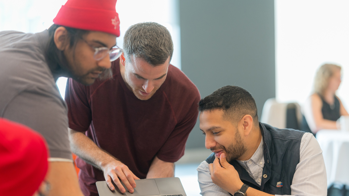 Three people gathered looking at a laptop screen