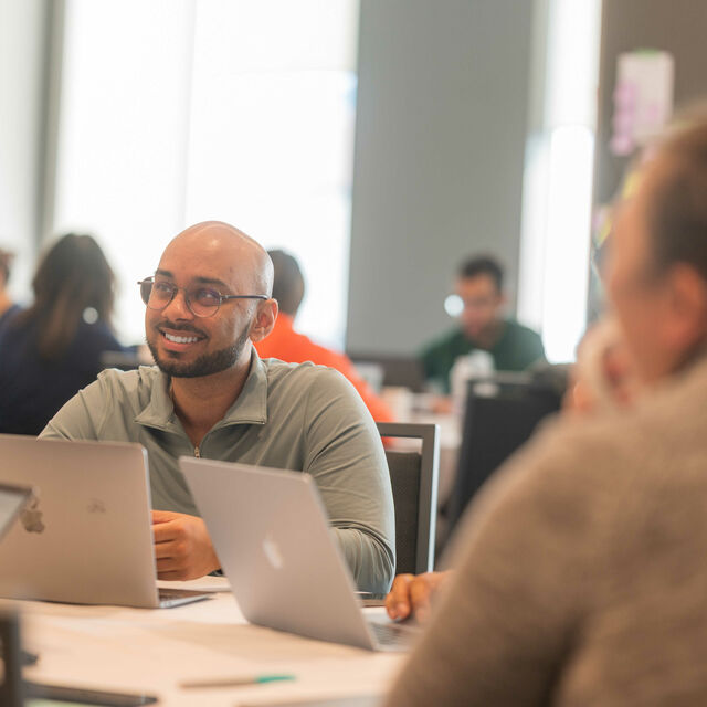 Person smiling sitting in front of a laptop.