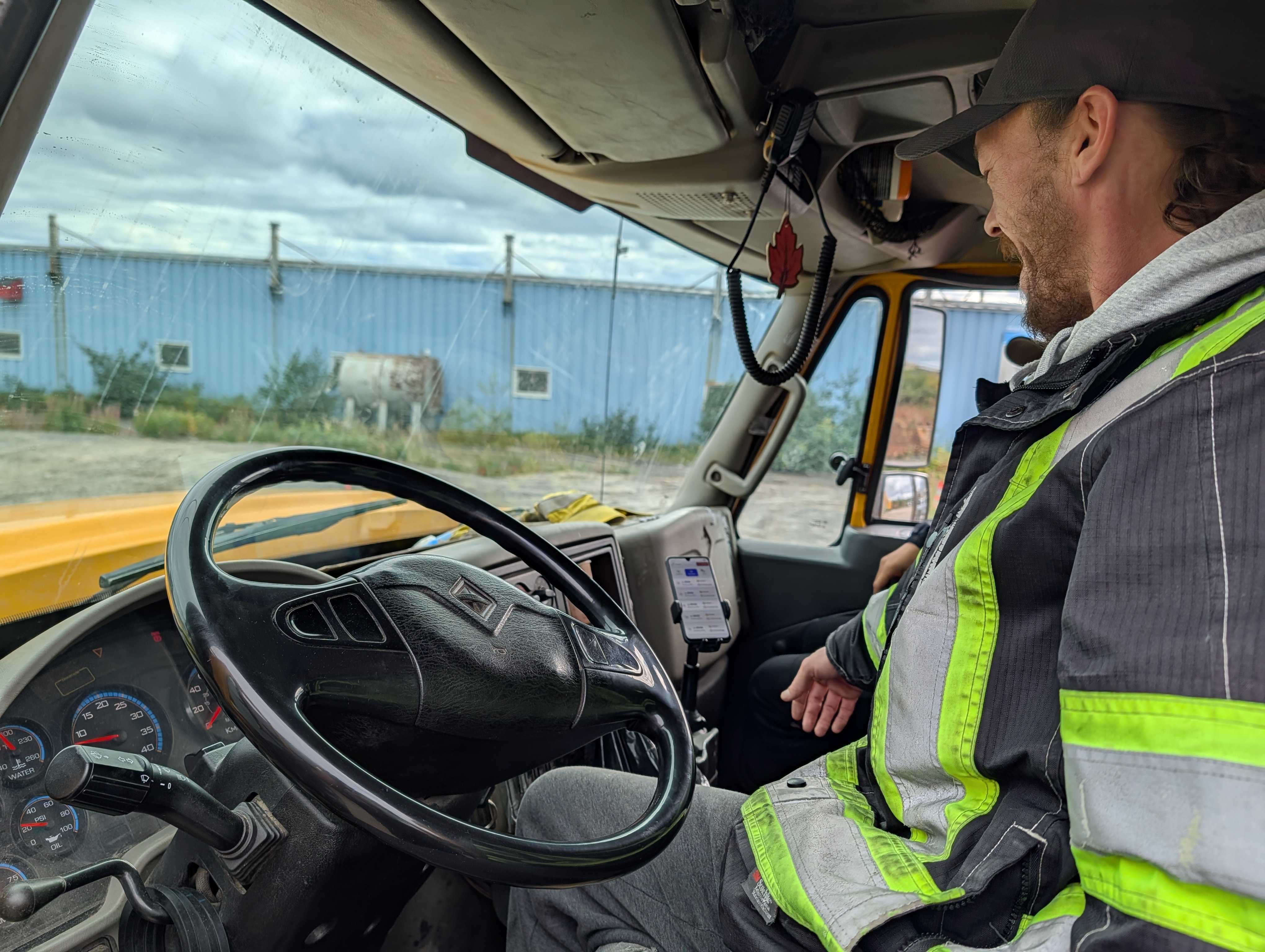 A drive sits in his truck, looking at a phone with the app installed.